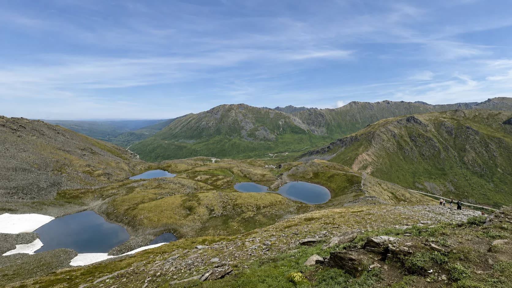 Alpine tarns and ponds seen from the April Bowl trail above Hatcher Pass, with hikers on the ridge path